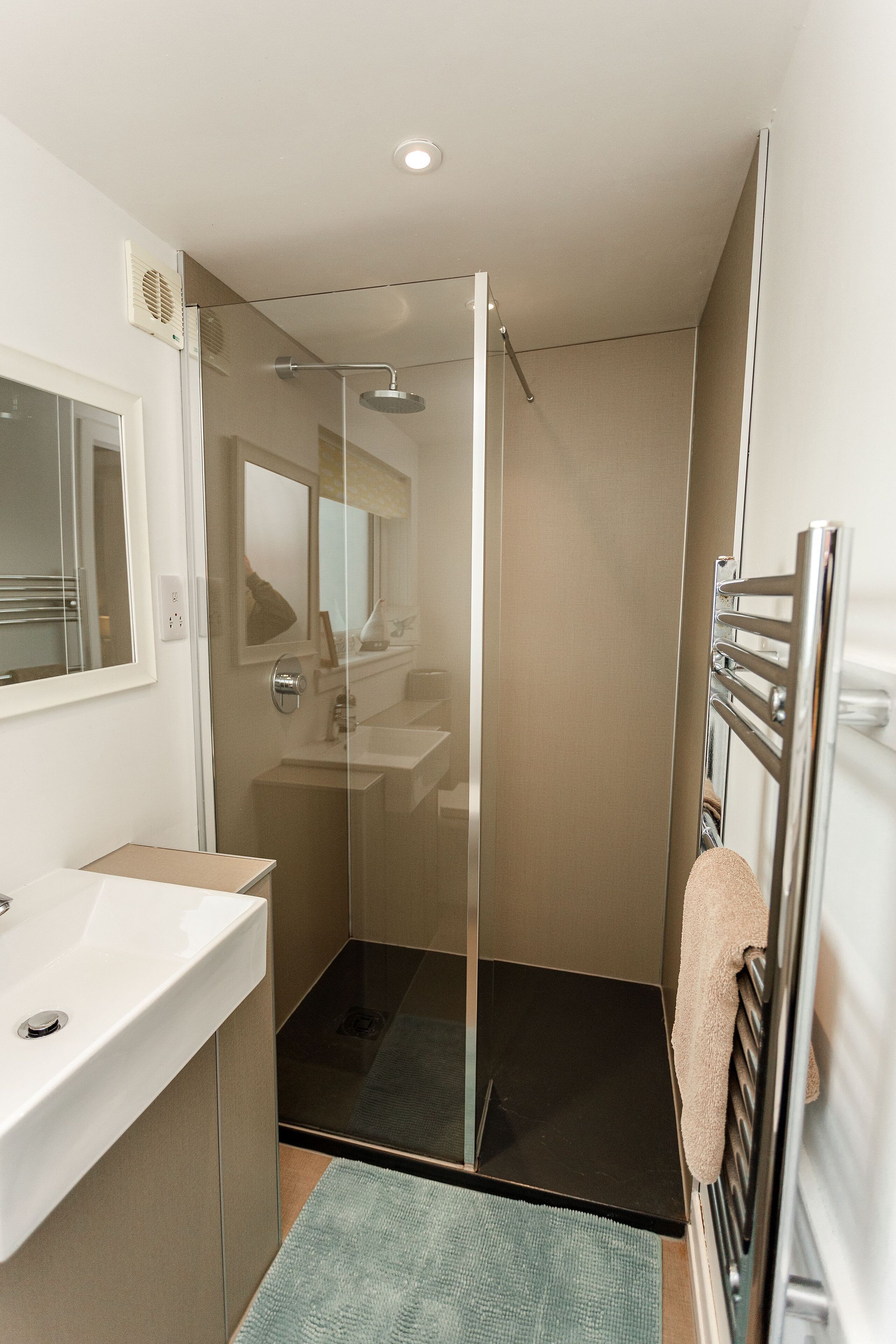 Une salle de bain moderne avec une douche à parois de verre, un lavabo blanc et un porte-serviettes.
