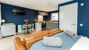 A compact living space with a kitchenette, a dining area, and a seating area with a sofa and a bed.