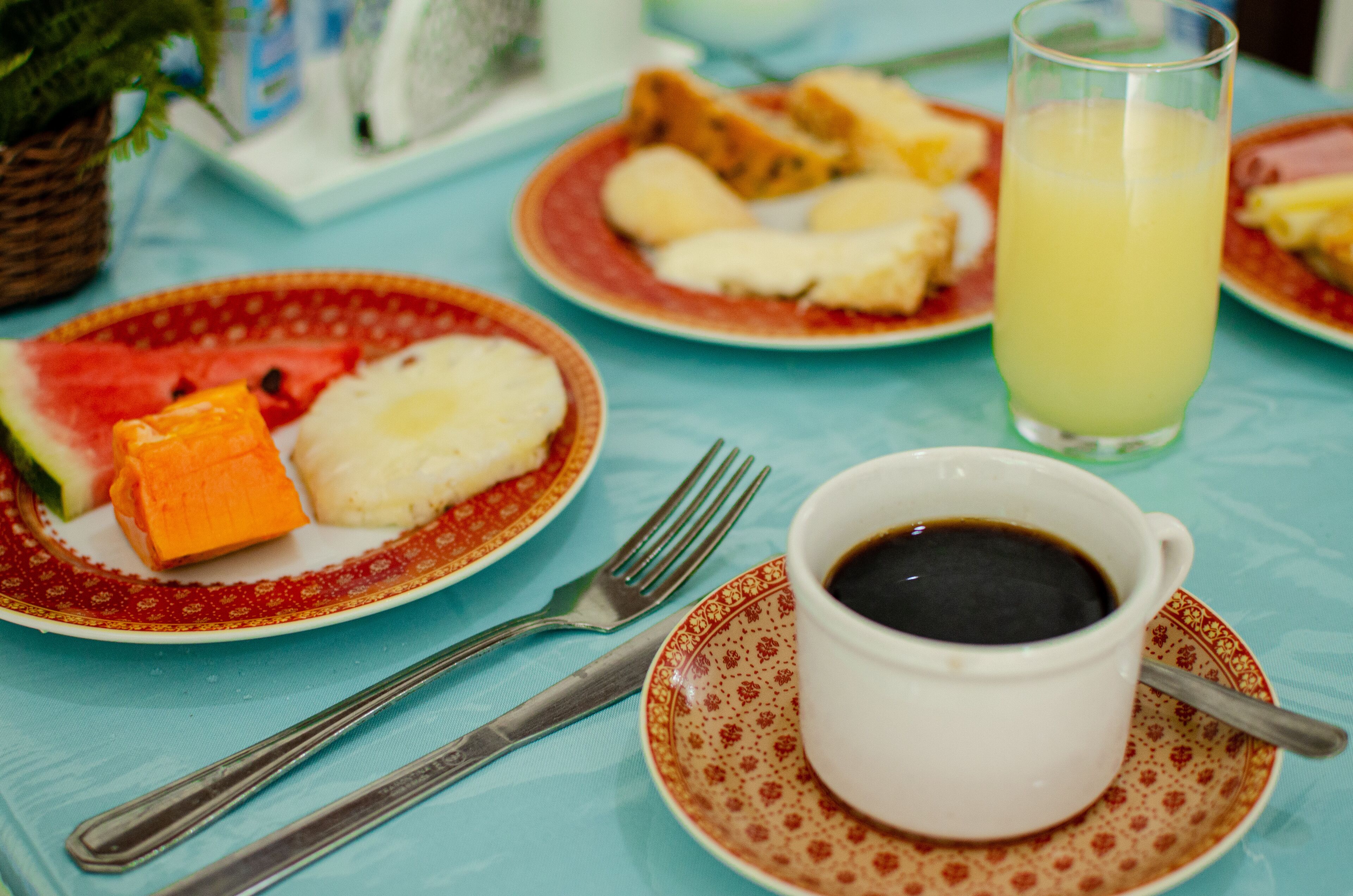 A breakfast setting with plates of food, a glass of juice, and a cup of coffee on a table.