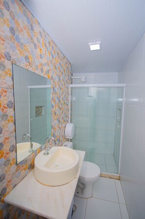 Une salle de bain équipée d’un lavabo, de toilettes et d’une douche à parois de verre.