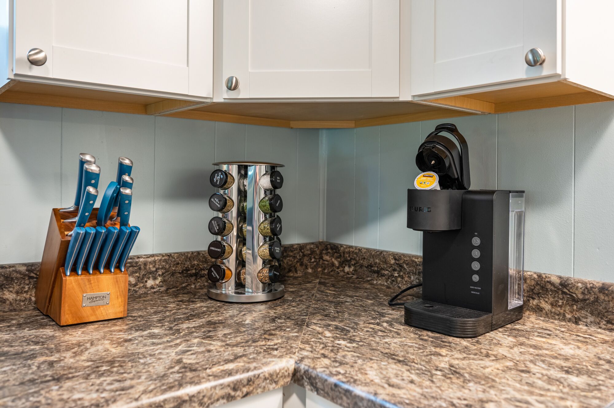A kitchen with a coffee maker, a spice rack, and a knife block.