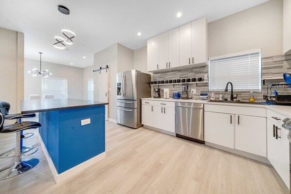 A modern kitchen with a blue island, stainless steel appliances, and white cabinetry. - Contemporary Couples Cache walking distance from AT&T Stadium (Arlington)