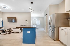 A modern kitchen with a central island, stainless steel appliances, and a dining area with chairs and a table.