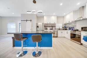 A modern kitchen with a central island, stainless steel appliances, and a blue accent wall.
