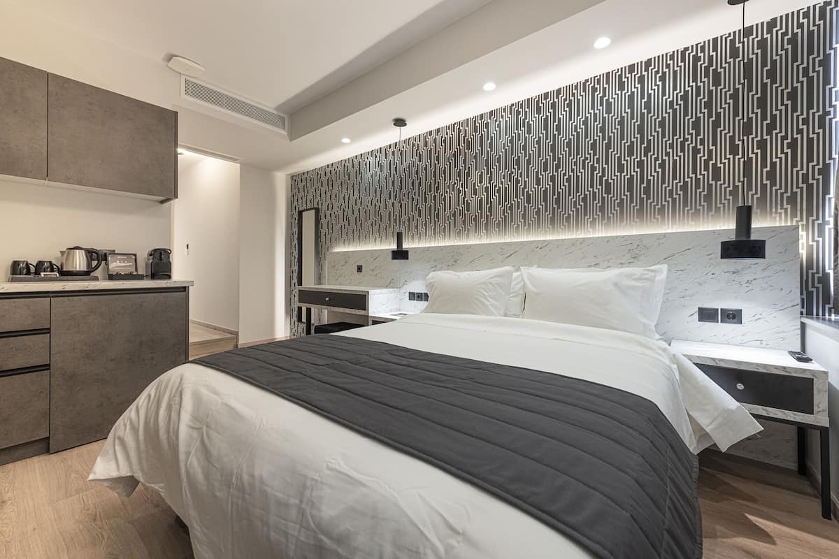 A modern bedroom with a large bed, bedside tables, a built-in desk, and a patterned wall.