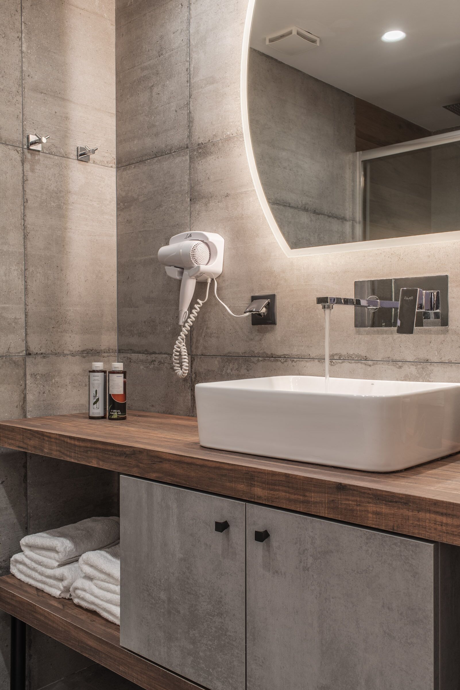 Un baño moderno con un lavamanos grande, un secador de pelo y un espejo.