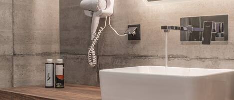 Un baño moderno con un lavamanos grande, un secador de pelo y un espejo.