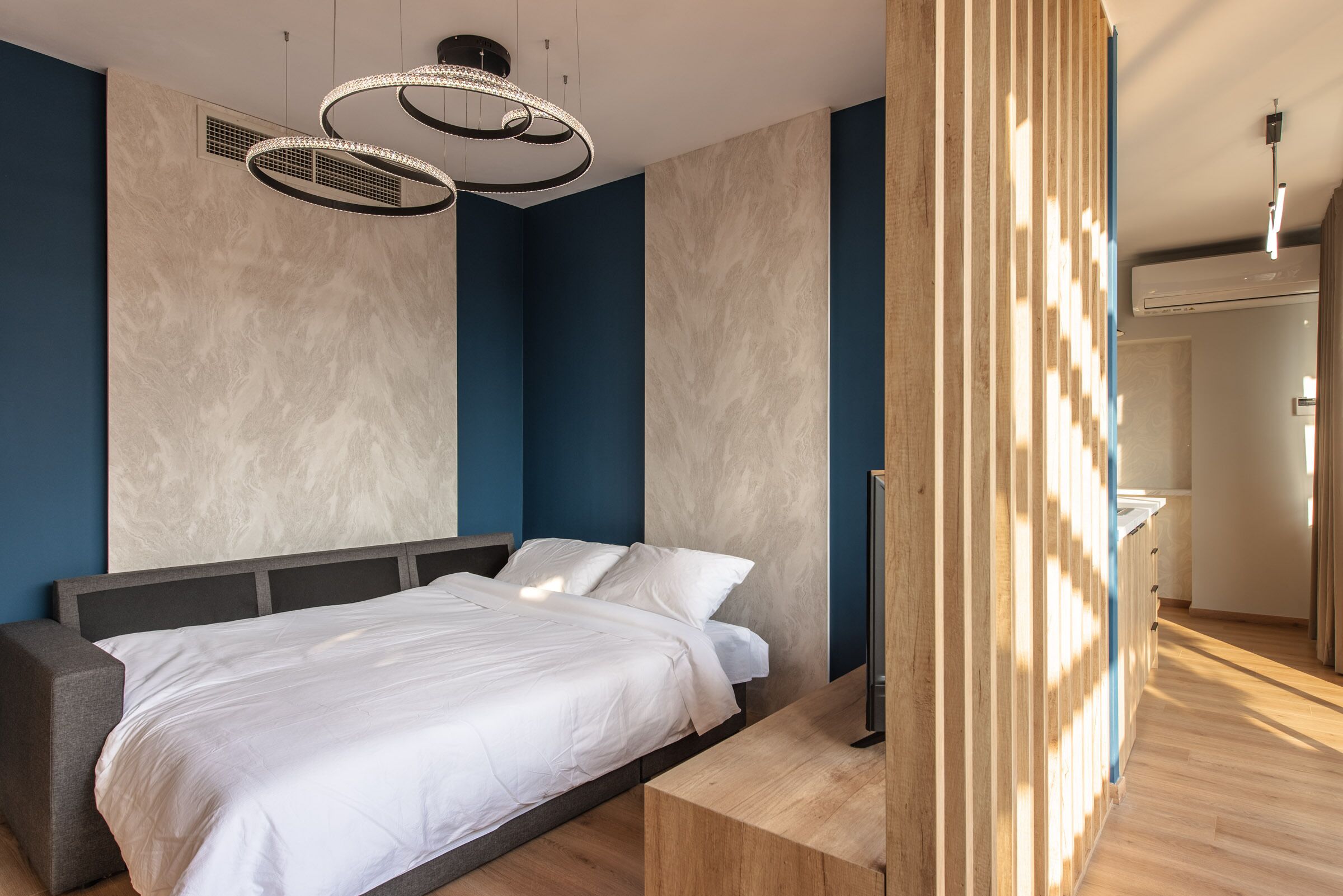 A modern bedroom with a bed, a wooden bedside table, and a unique lighting fixture.