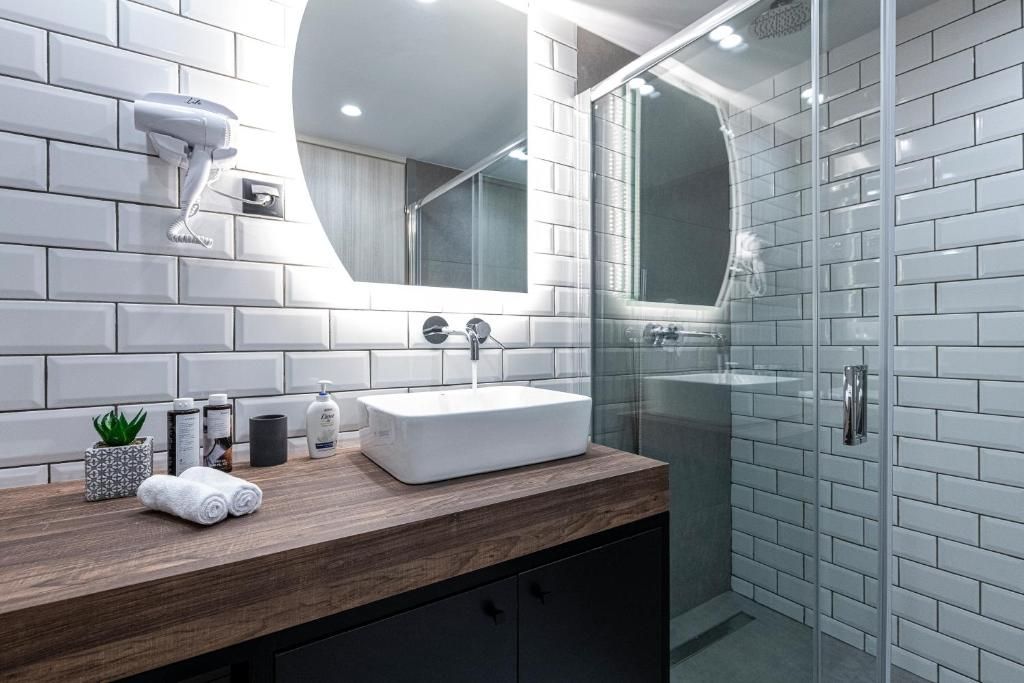 Een moderne badkamer met een witte wastafel, een ronde spiegel en een douche met glazen wanden.