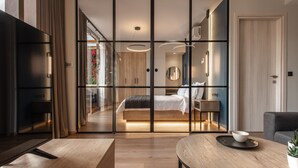 Un dormitorio moderno con cama, mesita de noche y vistas a un balcón con flores a través de un separador de vidrio.
