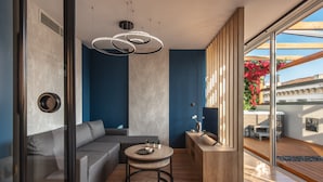 Una sala de estar moderna con un sofá gris, una mesa de centro redonda de madera y una mesita auxiliar de madera empotrada.