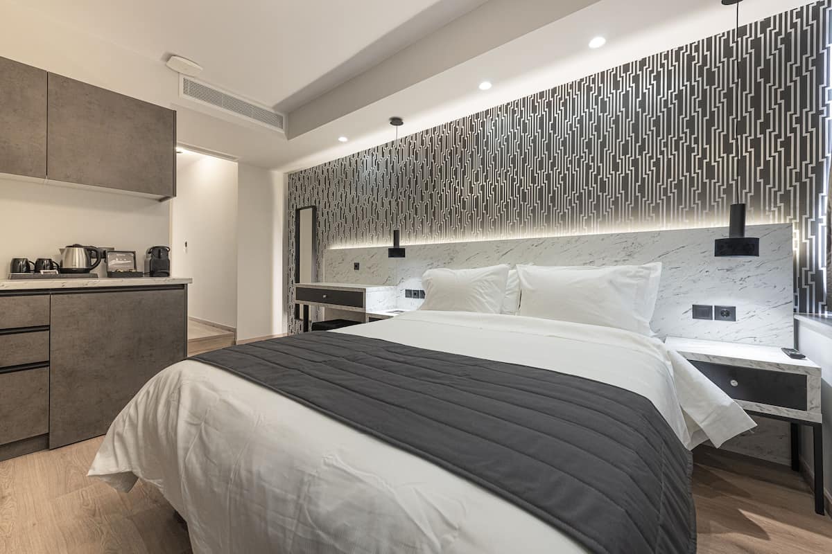 A modern bedroom with a large bed, bedside tables, a built-in desk, and a patterned wall.