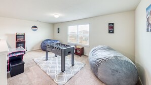 Een kamer met een tafelvoetbalspel, een relax fauteuil, een raam met jaloezieën.