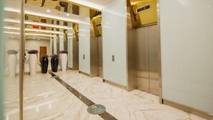 A modern elevator interior with marble flooring and glass doors.