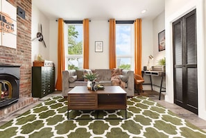 Cozy living room with a fireplace, sofa, and desk area.