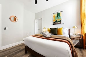 Relax in a spacious room with a large bed, bedside table, and cityscape artwork.