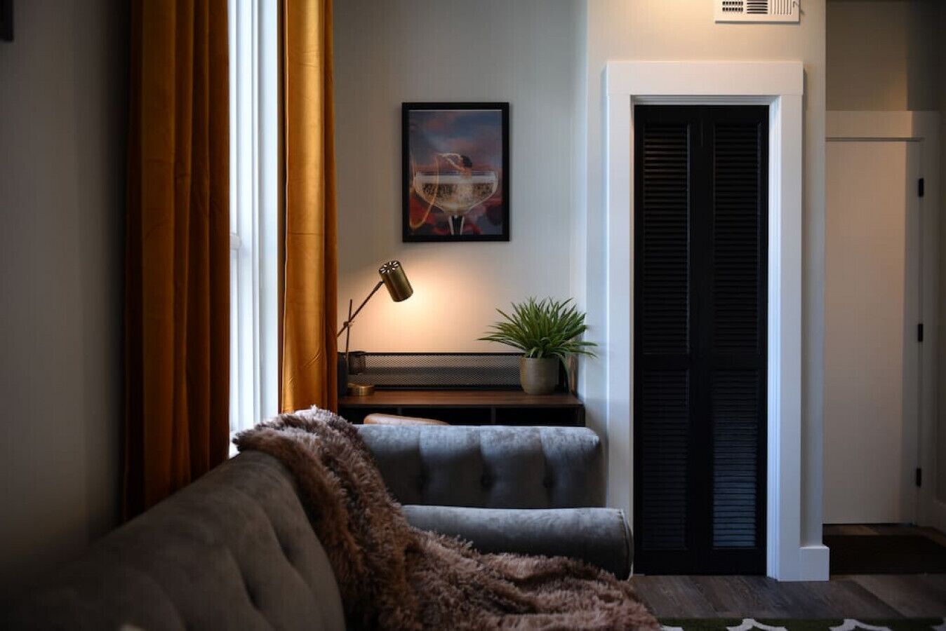 A cozy living room with a sofa, a bench, a lamp, and a potted plant.
