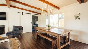 A spacious living room with a wooden dining table, a sofa, and a fireplace. - Family Retreat with Pool and Hot Tub (Vista)