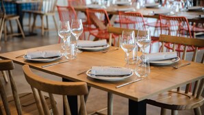 Un restaurante con mesas y sillas de madera, algunas con cojines rojos.
