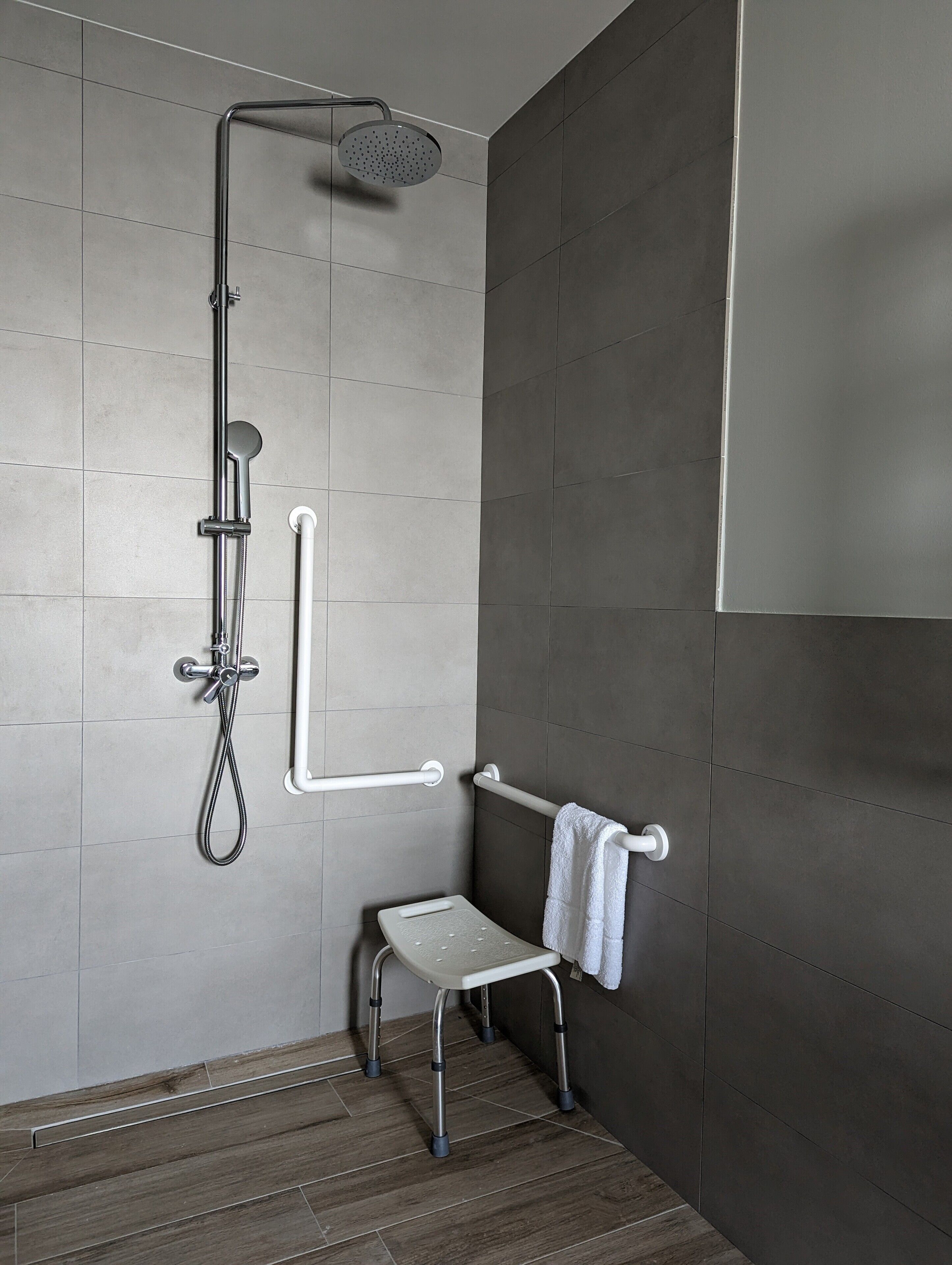Un espacio de ducha moderno con un cabezal de ducha de mano, una ducha de mano y una manguera para ducha.