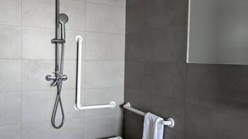 Un espacio de ducha moderno con un cabezal de ducha de mano, una ducha de mano y una manguera para ducha.