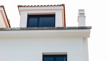 A building with a white facade, a blue window, and a red-tiled roof.