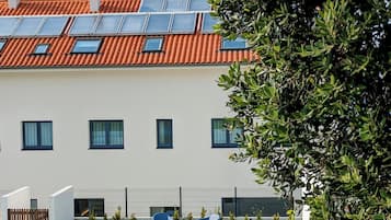 Un edificio moderno con tejado de tejas rojas, numerosas ventanas y paneles solares.