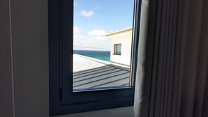 Una habitación con ventana que da a un balcón y al mar.