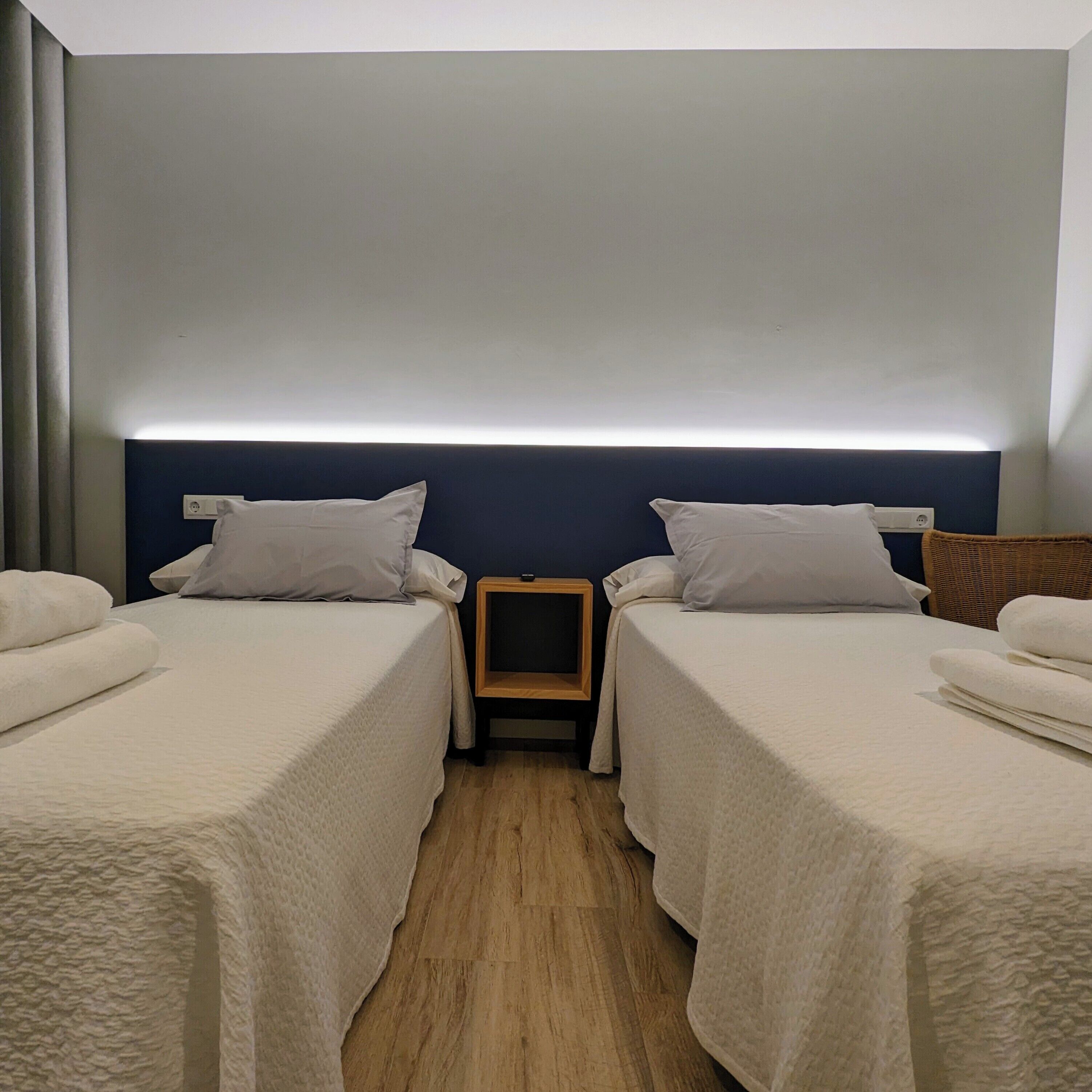 A hotel room with two single beds, a bedside table, and a nightstand.