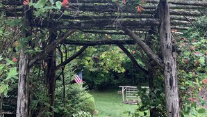 Ein Garten mit einer Holzpergola, einem Kiesweg und einer amerikanischen Flagge.