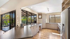 A modern kitchen with a large island, built-in appliances, and a view of the outdoor garden. - Mudjimba Escape - Pet friendly, luxury villa w/pool (Sunshine Coast)