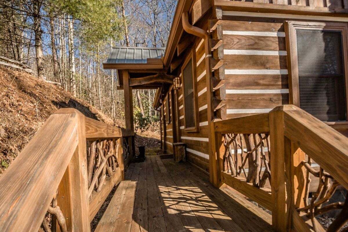 A wooden cabin with a covered porch and a wooden deck.