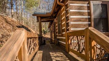 A wooden cabin with a covered porch and a wooden deck.