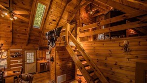 Ein rustikales Blockhaus-Interieur mit Holzwänden, einer Treppe, einem Essbereich und einer Küche.