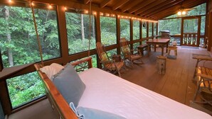 Eine Holzhütte mit einem Bett, Schaukelstühlen und einem Esstisch.
