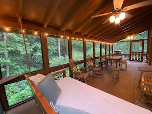 A wooden cabin with a bed, rocking chairs, and a dining table.