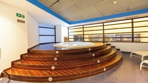 A modern indoor spa area with a wooden spiral staircase leading to a hot tub, large windows, and a ceiling with a grid pattern. - GPP - Grand Plaza Paulista By Anora Spaces (São Paulo)
