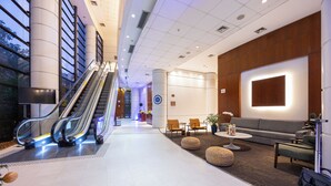 A modern lobby with an escalator, seating area, and a large illuminated screen. - GPP - Grand Plaza Paulista By Anora Spaces (São Paulo)