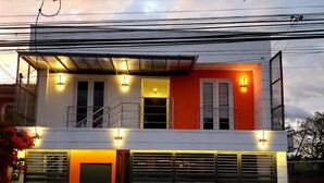 A modern two-story house with a balcony, large windows, and a garage. - Habitación Independiente #2 , Entre Airport y SJ, Privada (Uruca)