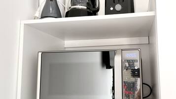 A kitchen with a microwave, coffee maker, and toaster on a white shelf.
