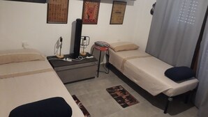 A small, compact room with two single beds, a desk with a chair, a small table with a chair, and a wall-mounted shelf. - Beach and relax. history and events. Everything at your fingertips. (Francavilla al Mare)