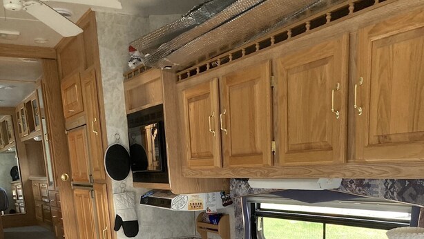 A compact kitchen with wooden cabinets, a built-in microwave, and a window providing a view outside. -  Camping, but more comfy  (Tetonia)