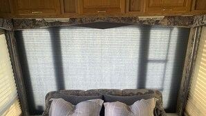 A bedroom with a bed, pillows, a bedside table, and a window with blinds. -  Camping, but more comfy  (Tetonia)