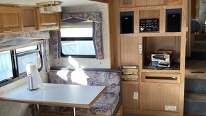 A compact RV kitchen with a dining area, built-in appliances, and a clock. -  Camping, but more comfy  (Tetonia)