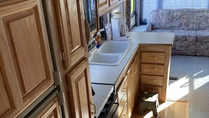 A compact RV kitchen with wooden cabinets, a sink, and a stove. -  Camping, but more comfy  (Tetonia)