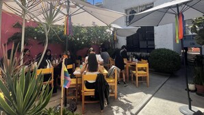 An outdoor seating area with tables and chairs, surrounded by potted plants and umbrellas providing shade. - Casa Madera (Lagos de Moreno)