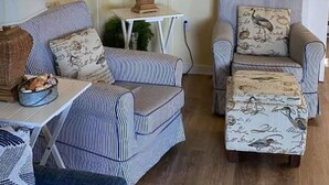 A cozy living room with striped armchairs, a small table, a lamp, and a framed picture on the wall. - Floating Cottage on the River "Nantucket" (Sabula)