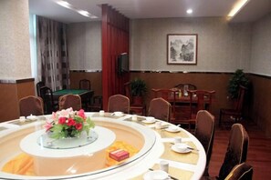 Un salón de conferencias con una mesa redonda, sillas y una pequeña televisión en la pared.