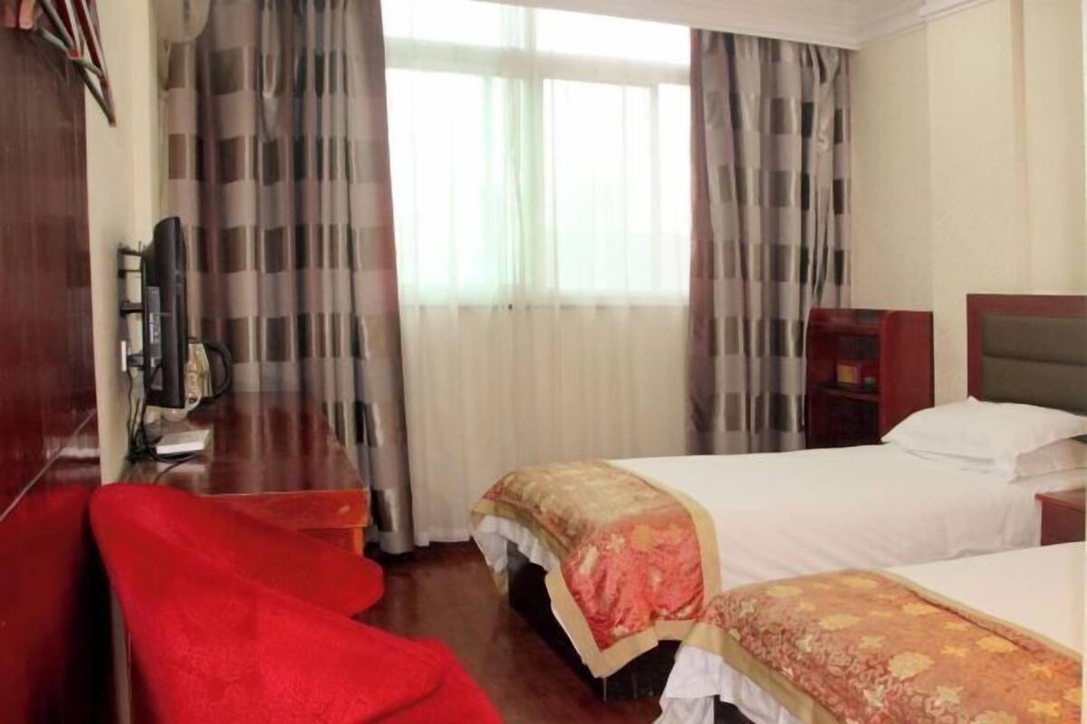 Een hotelkamer met twee bedden, een bureau, een stoel en een televisie.