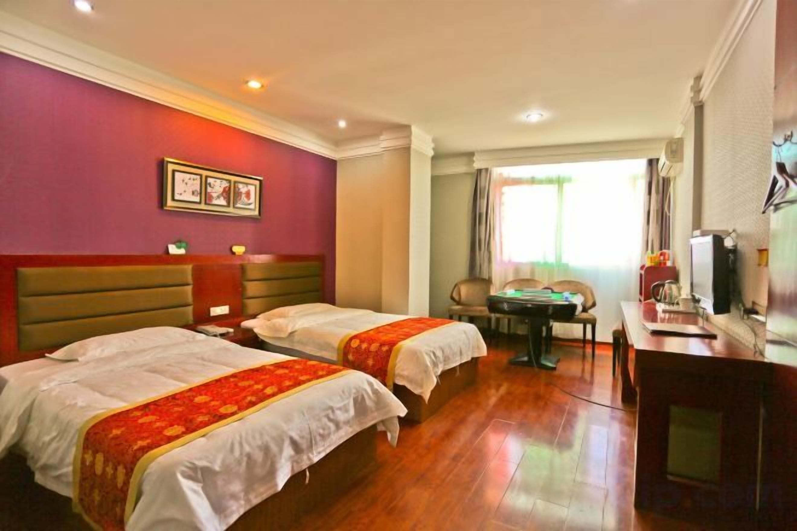 A hotel room with two beds, a desk, a chair, and a television.
